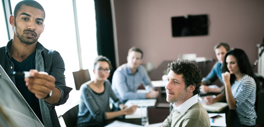 Man presenting to a table of people in a conference room