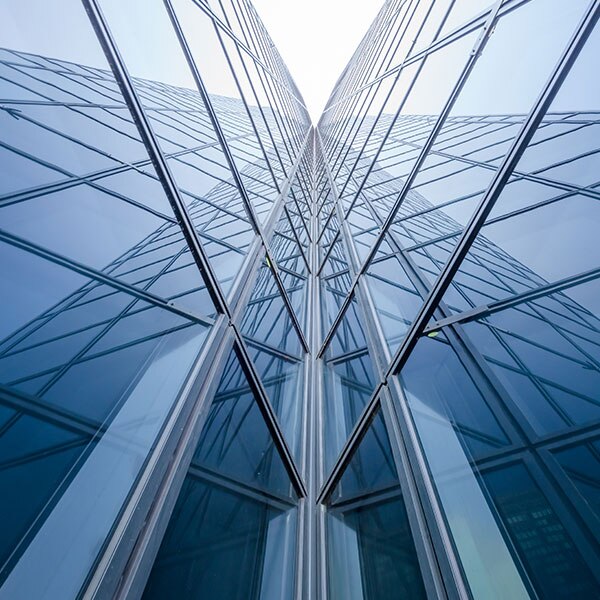 An abstract upward view of a modern glass-clad skyscraper