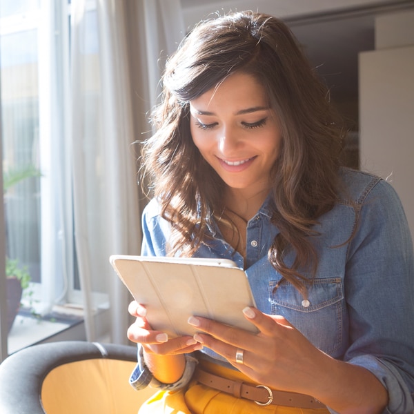 A woman standing by a window with a tablet
