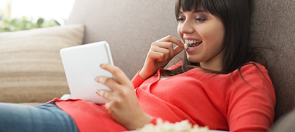 Woman eating popcorn on the couch.