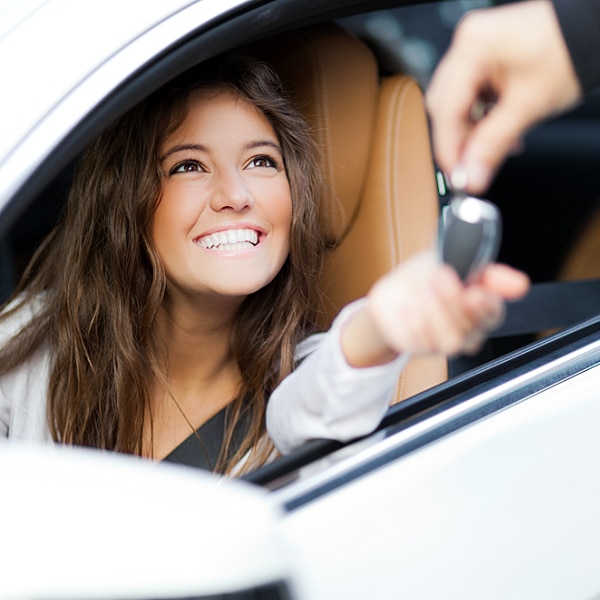 Happy young woman in car