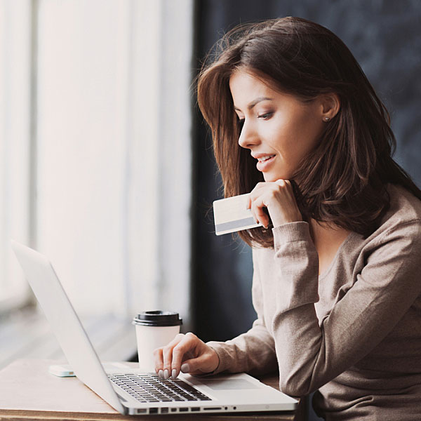 Woman holding credit card looking at laptop