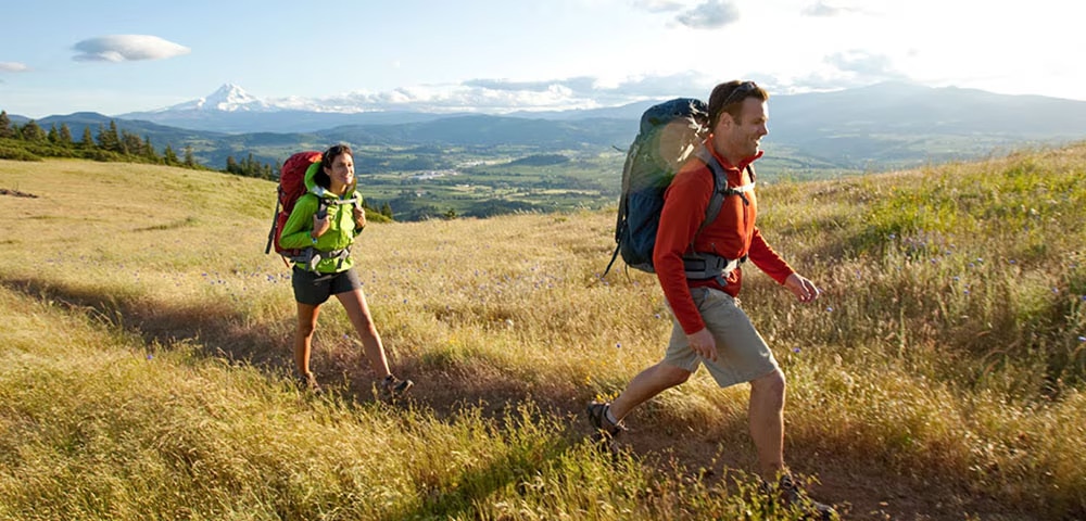 Two people hiking through field