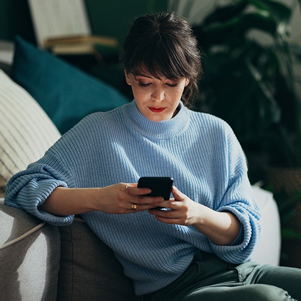 Woman sitting on couch looking at phone
