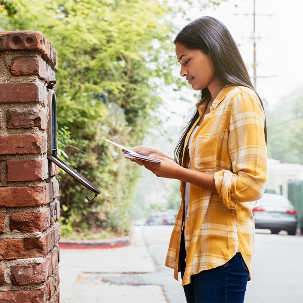 Woman standing at mailbox reading mail