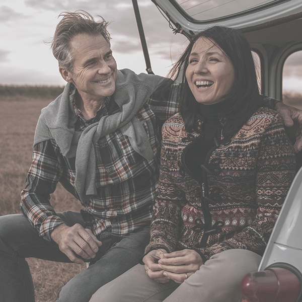 Man and woman sitting on tailgate laughing 