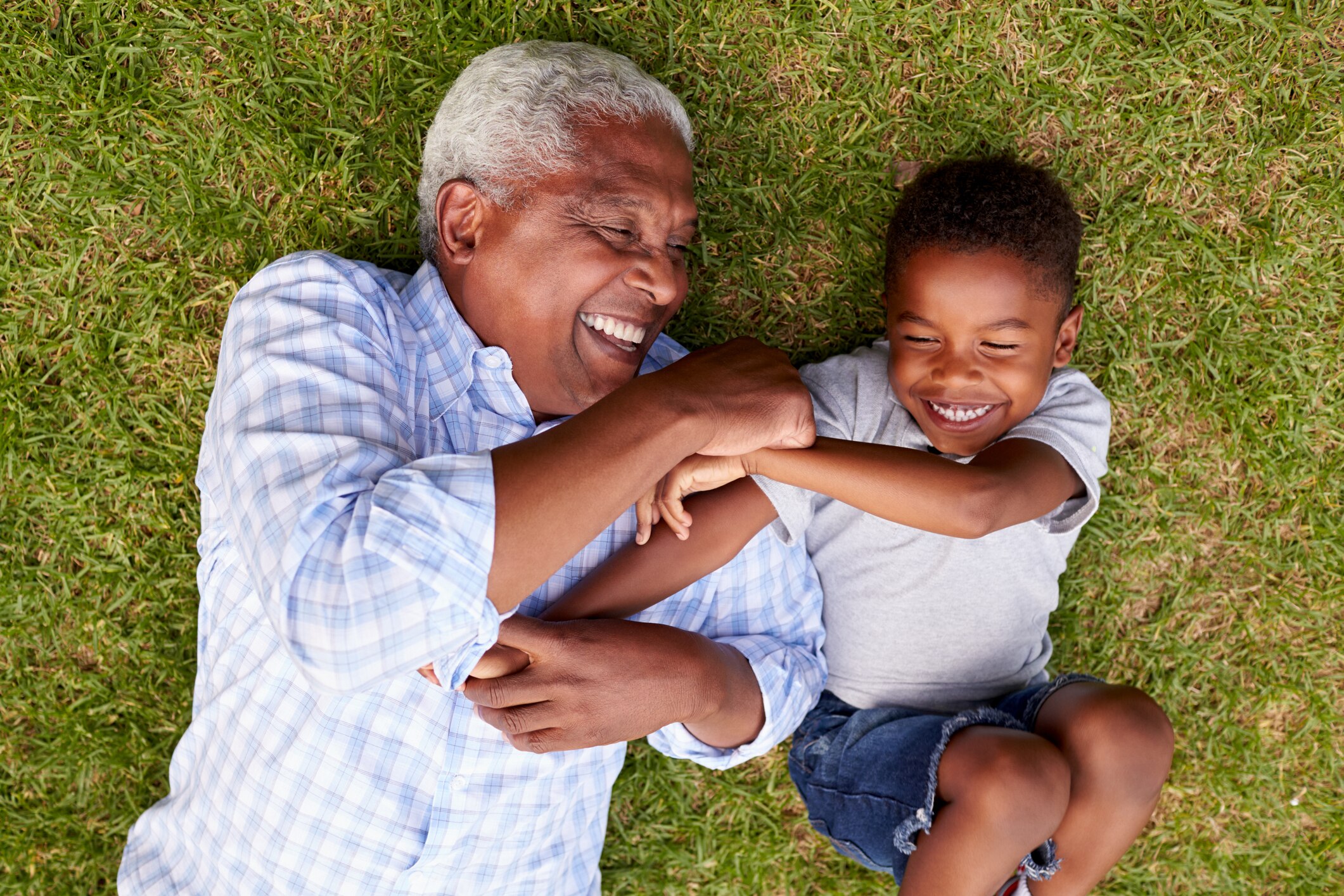A grandpa and grandson lying on the ground laughing together