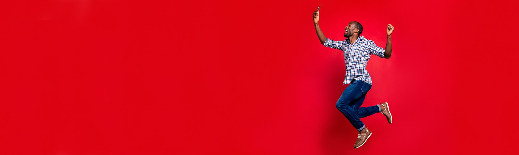 man jumping in air and smiling at phone