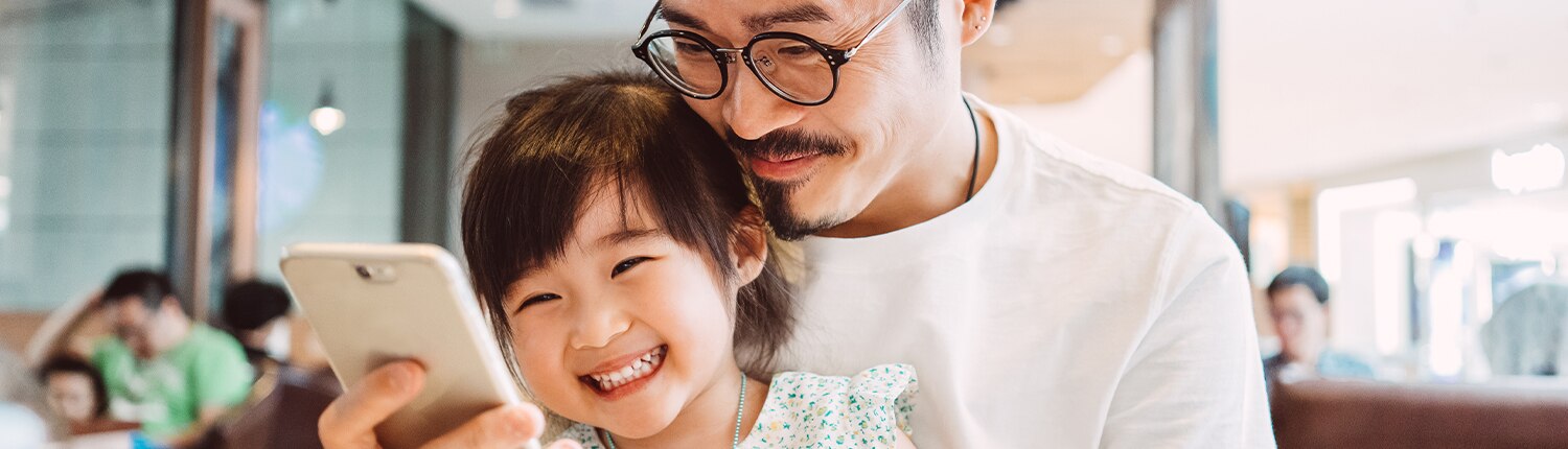 father and daughter looking at a phone