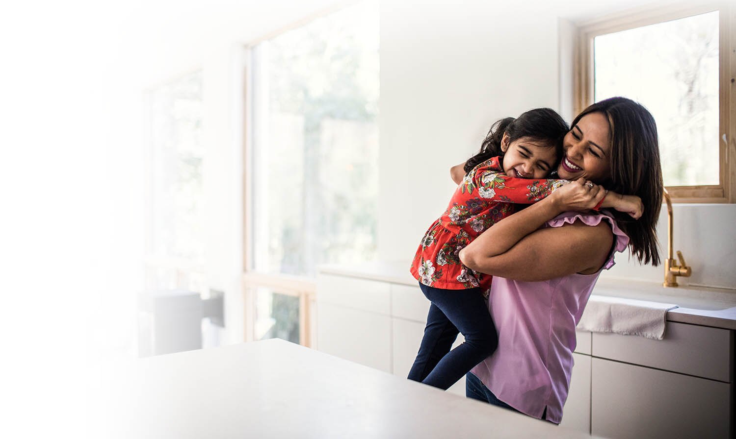 mom holding daughter in the kitchen