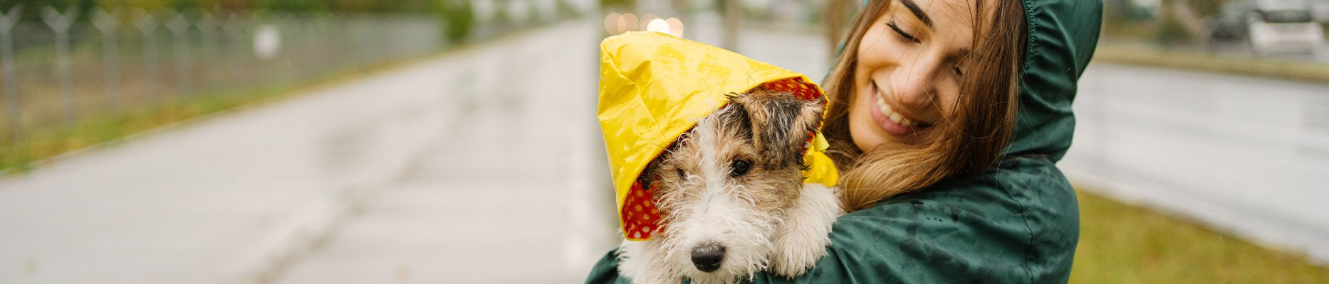 woman holding a dog in a rain coat