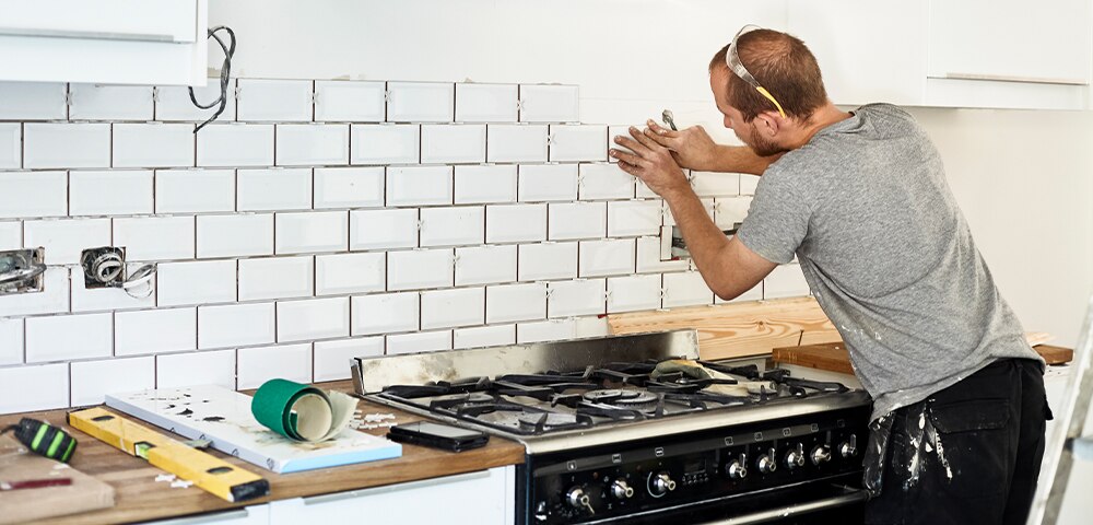man tiling kitchen wall