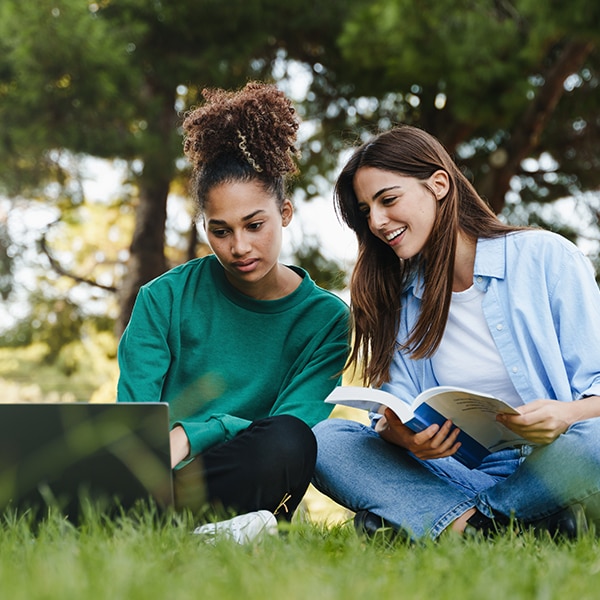 Two Female Students Sitting on Grass