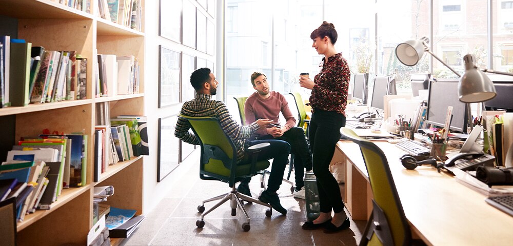 one woman and two men in a team discussion at the office