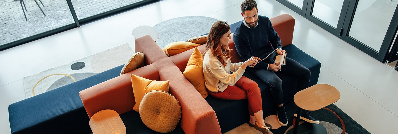 man and woman sitting on couch looking at tablet