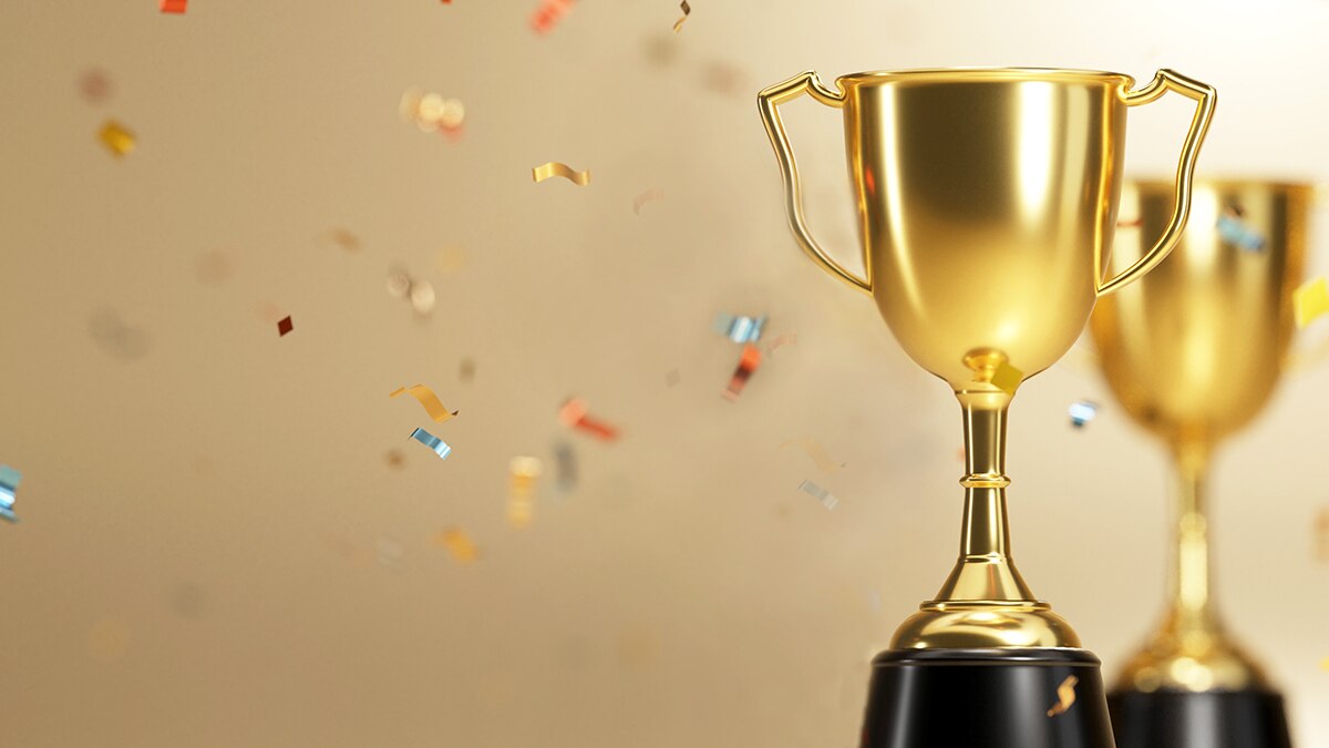 golden trophy award with falling confetti on gold background. copy space for text. 3d rendering.