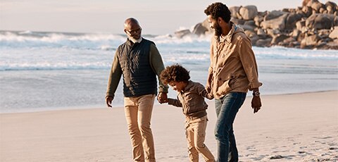 Multigenerational family walking on beach holding hands