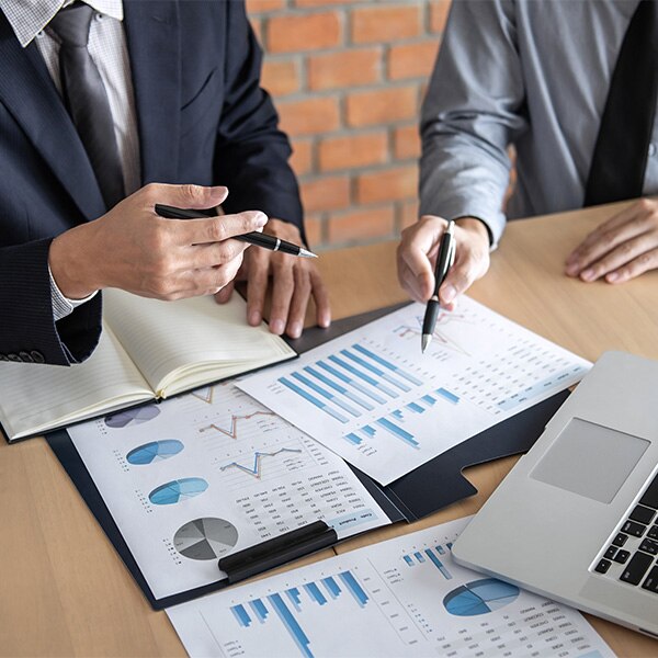 Business meeting with charts and graphs scattered across table