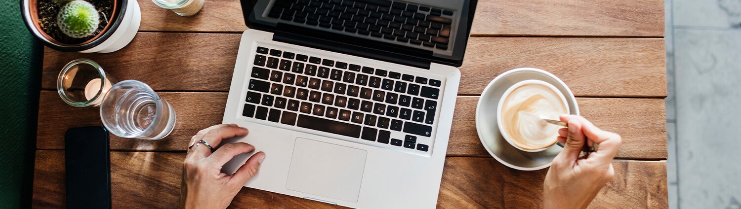 Overhead view of woman at computer drinking coffee